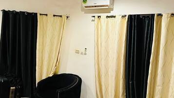 A hotel room with a bed, a chair, a small table, and a ceiling fan.