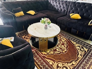 A black sofa with gold accents and a round coffee table with a marble top. - Villa Amina Splendid Elegant Structure (Ouagadougou)