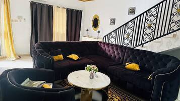 Un salon avec un canapé de couleur foncée, une table basse ronde et un tapis à motifs.