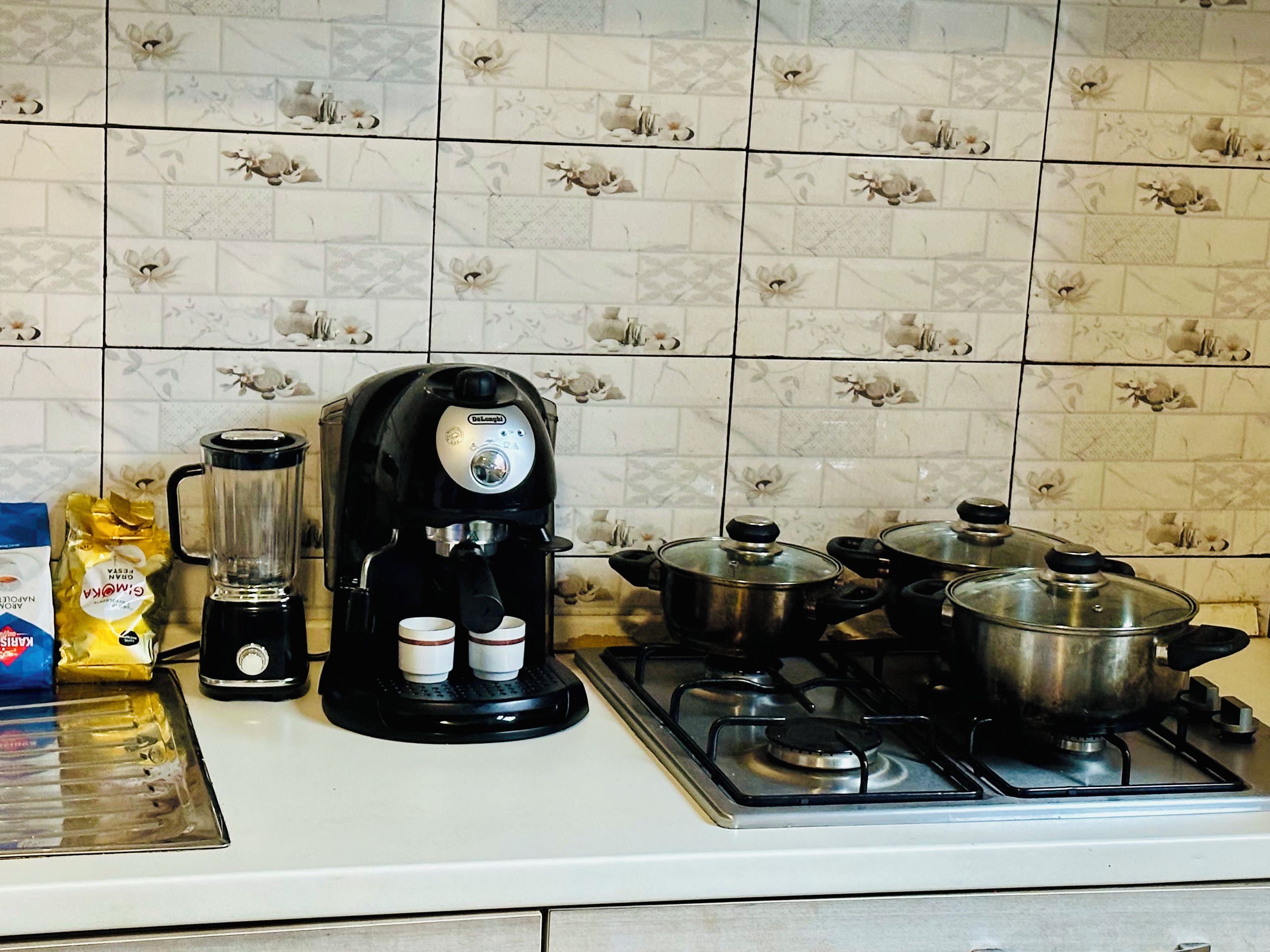 Une cuisine équipée d’une machine à café, de casseroles et d’un paquet d’en-cas.