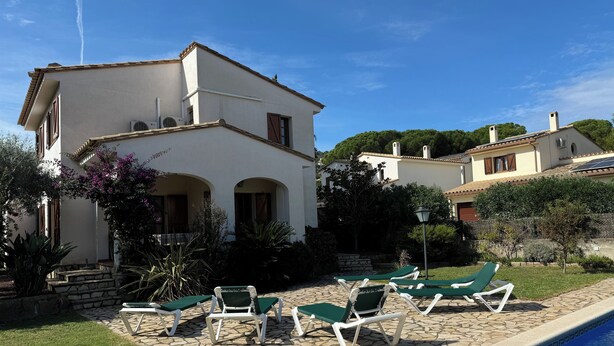 A villa with a swimming pool, outdoor seating, and a garden.