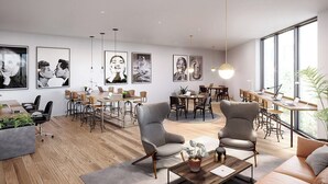 Un espace de vie et de salle à manger moderne, à plan ouvert, doté d’un plancher en bois, de fauteuils gris et d’une grande fenêtre qui laisse entrer la lumière naturelle.