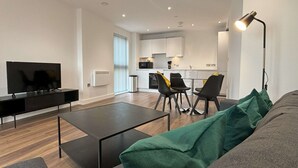 Un salon moderne doté d’un téléviseur à écran plat, d’un canapé, d’une table basse et d’un coin repas avec des chaises.
