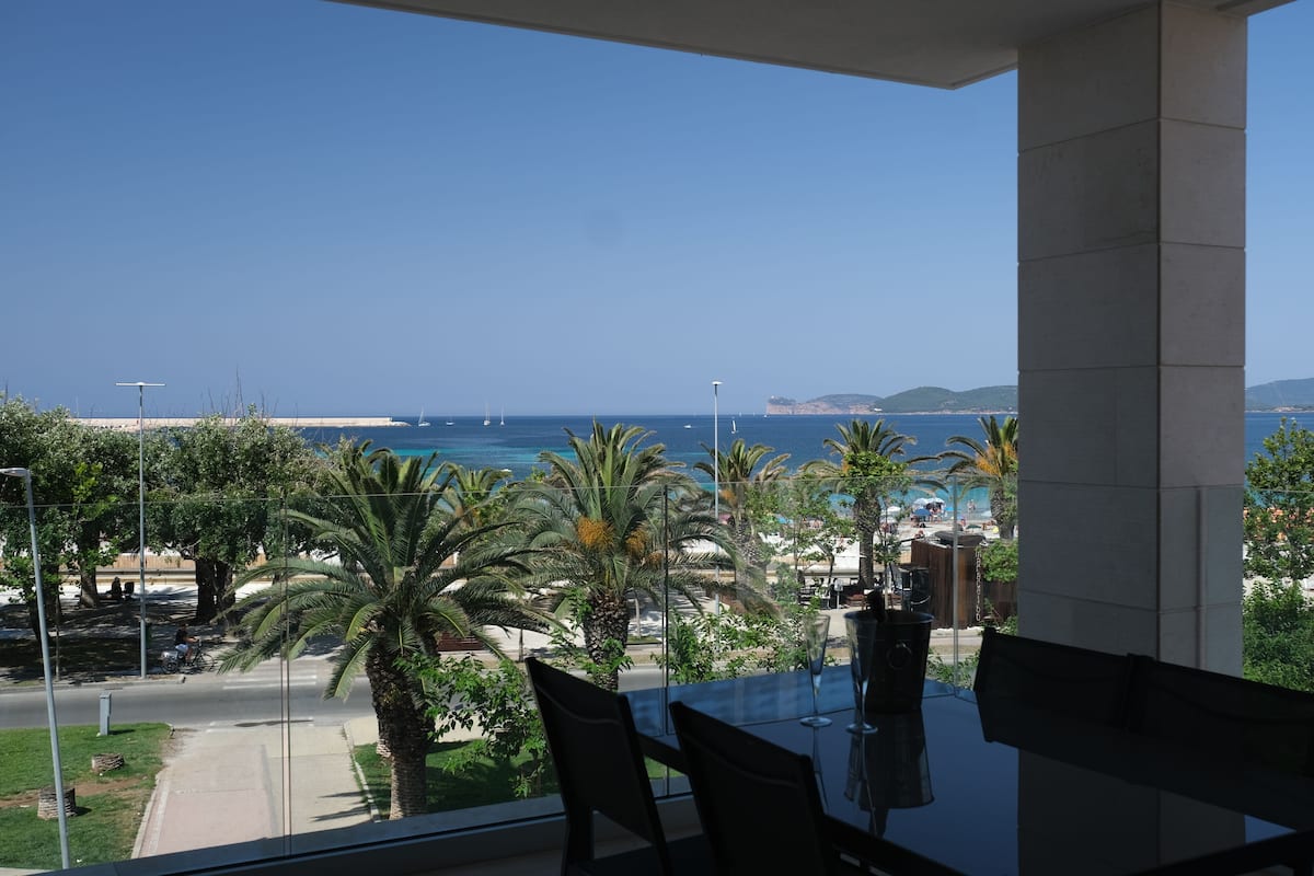 Ein Balkon mit Blick auf das Meer, Palmen und einen fernen Strand.