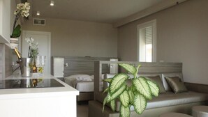 A modern living room with a sofa, a coffee table, and a potted plant. - AlMar Apartments by Alma di Alghero (Alghero)