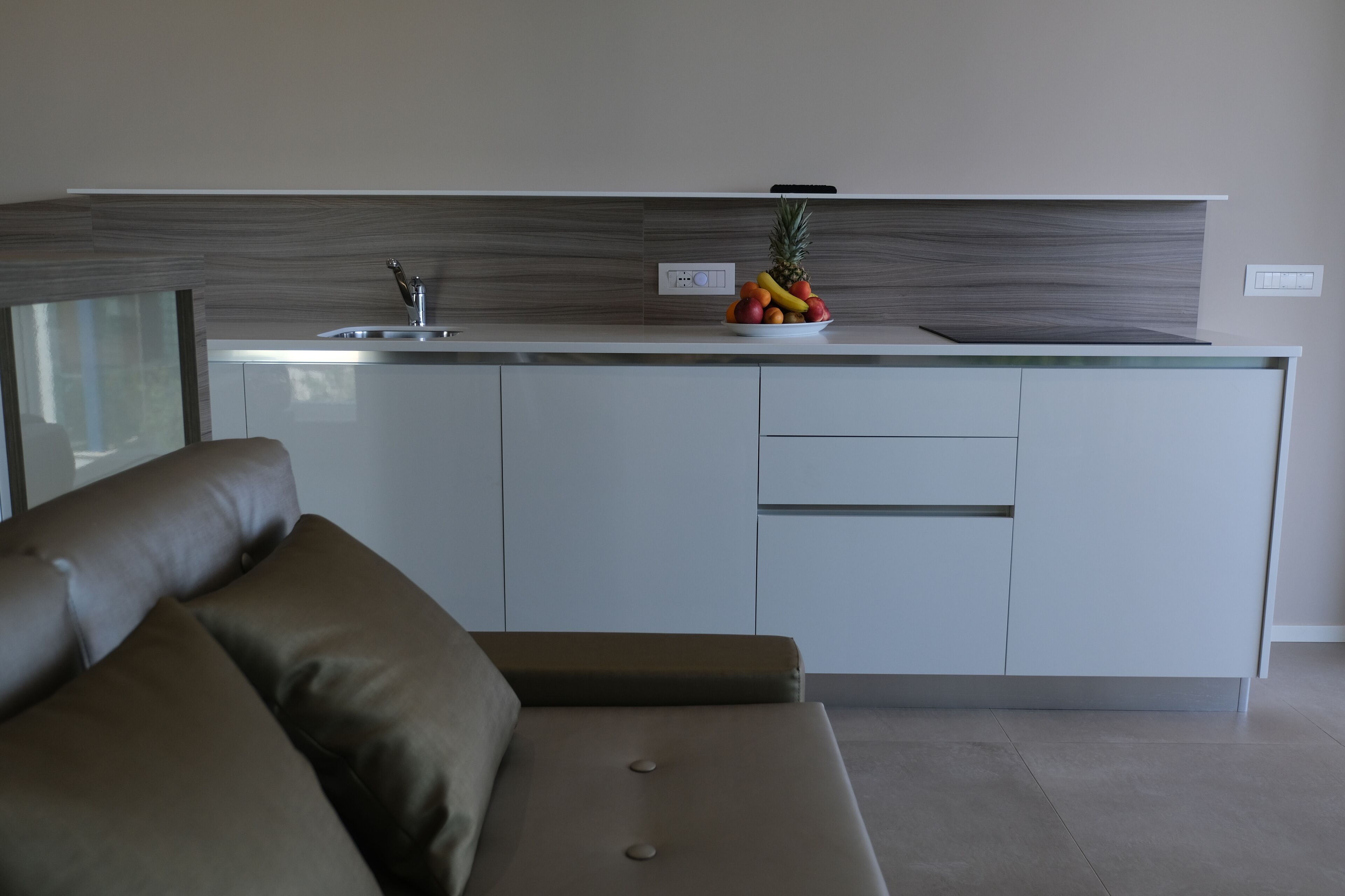 A modern kitchen with a built-in island, white cabinets, and a fruit bowl on the countertop.