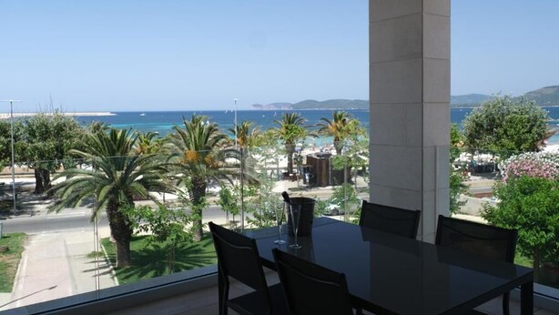 A dining area with a view of the sea, palm trees, and a clear sky. - AlMar Apartments by Alma di Alghero (Alghero)