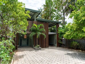 A modern building with a covered entrance, surrounded by lush greenery and a paved courtyard. - Moi Dambulla by DBI (Sigiriya)