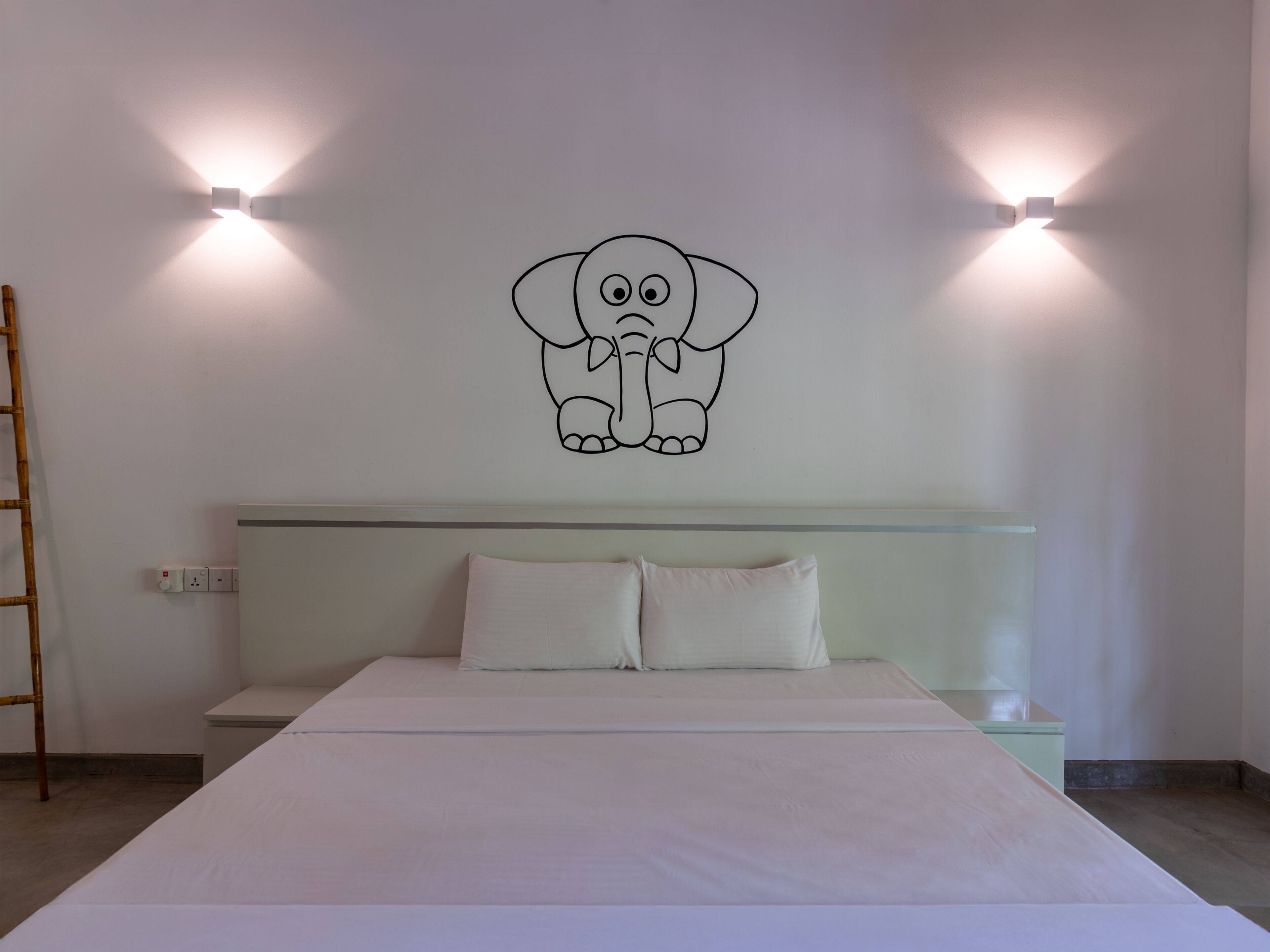 Ein Schlafzimmer mit einem Bett, zwei Kissen, einem Kopfteil und einer Elefanten-Wandsticker.
