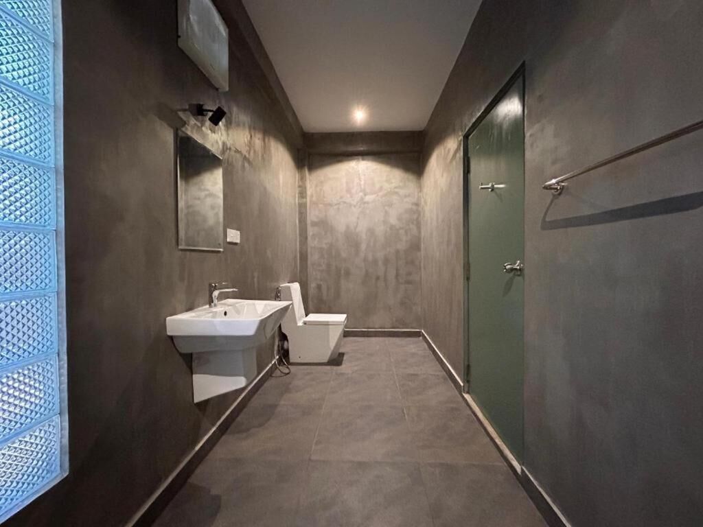 Casa de banho moderna com lavatório, sanita e cabine de duche com porta de vidro.