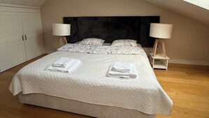 A bedroom with a large bed, two bedside tables with lamps, a ceiling light, and a skylight. - Stylish Duplex in Tallinn’s Old Town with Fast WiFi  (Tallinn)