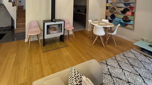 A spacious living area with a high ceiling, wooden beams, a dining table with chairs, a sofa, and a painting on the wall. - Stylish Duplex in Tallinn’s Old Town with Fast WiFi  (Tallinn)
