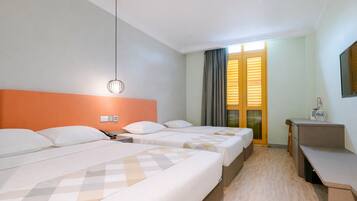 A hotel room with three beds, a desk, a chair, a mirror, and a window with blinds.