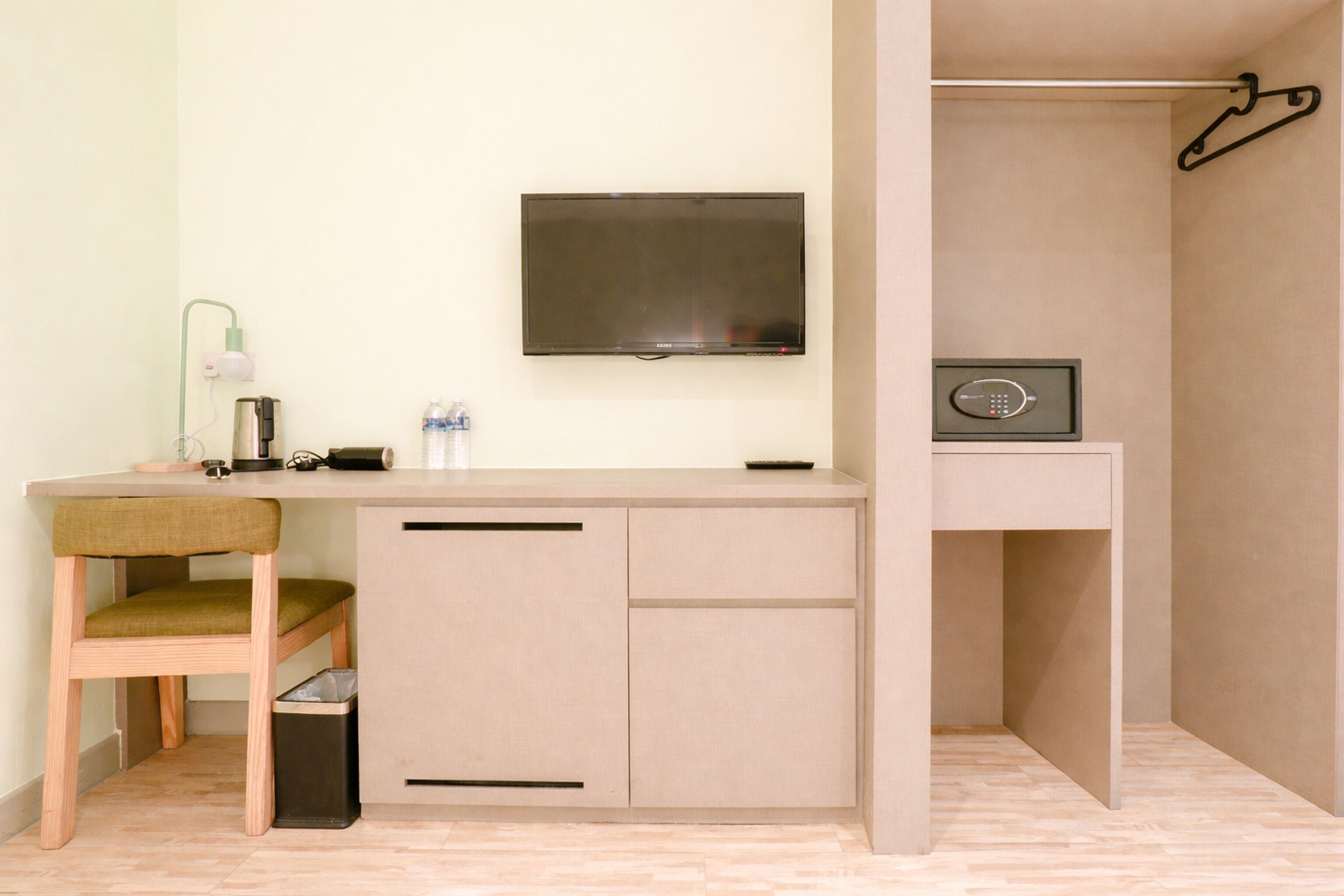 A compact room with a desk, chair, TV, and a safe.