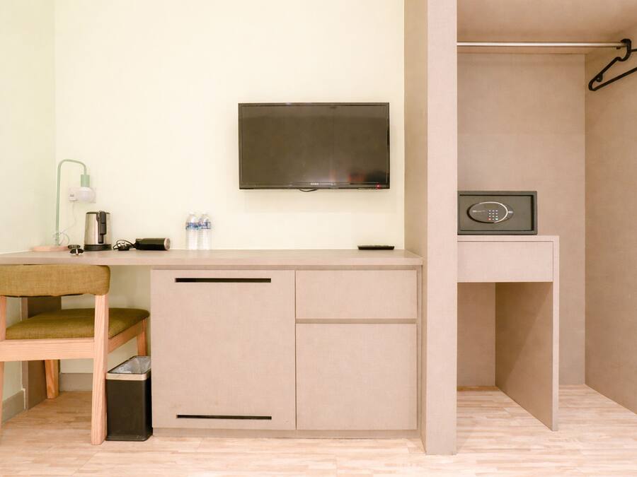 A compact room with a desk, chair, TV, and a safe.