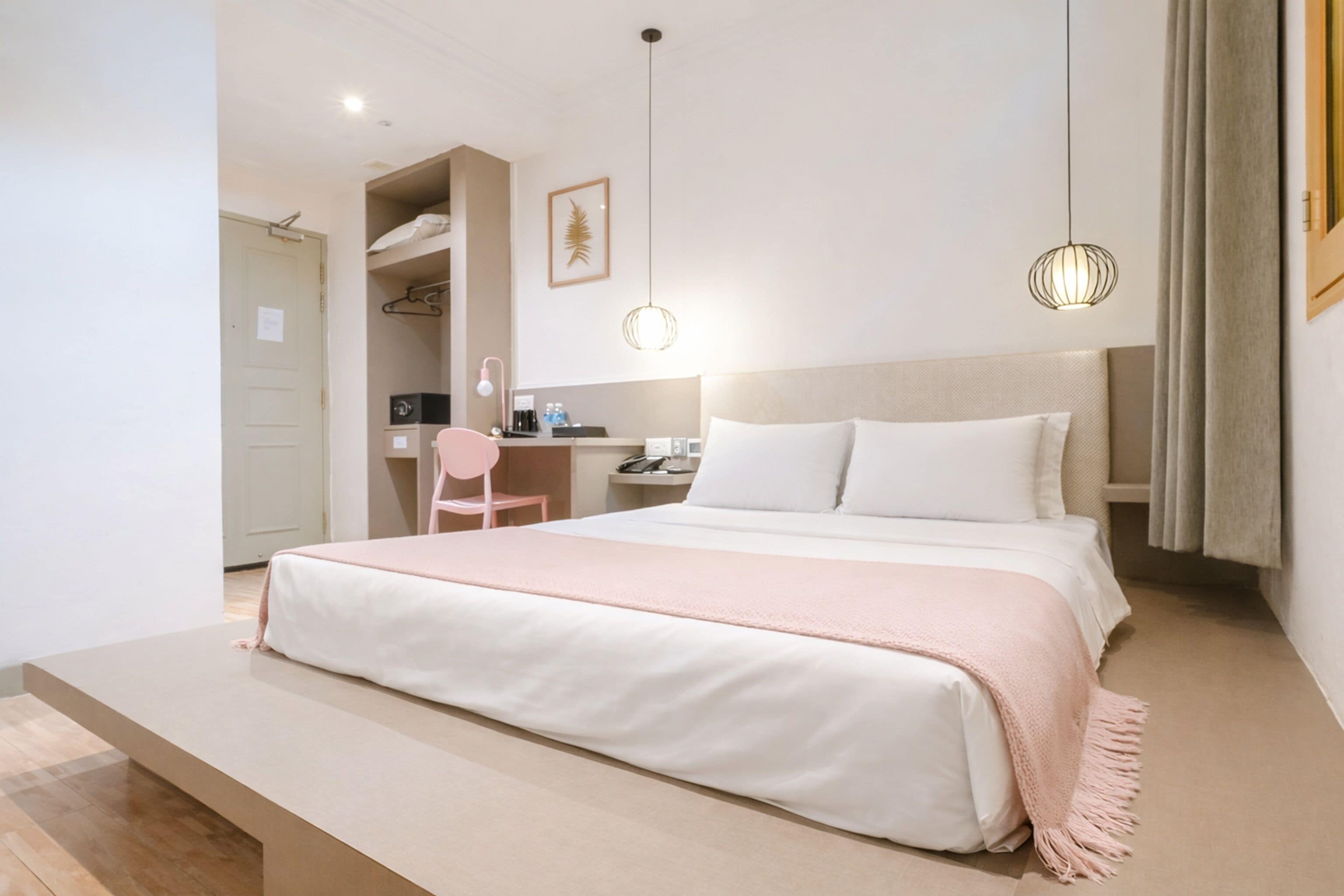 A modern hotel room with a large bed, a desk, and a chair.