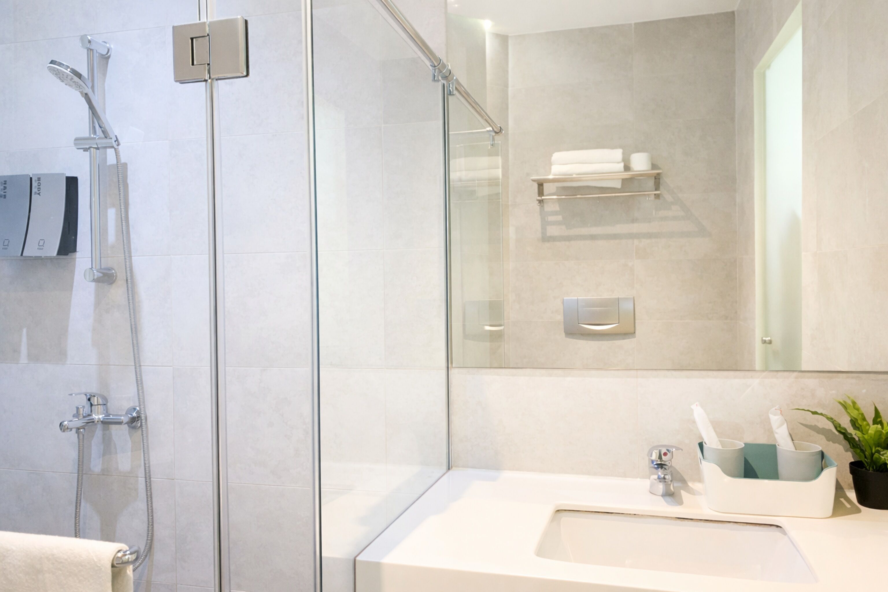 Un baño moderno con cabina de ducha de vidrio, un lavabo blanco y un perchero para toallas.