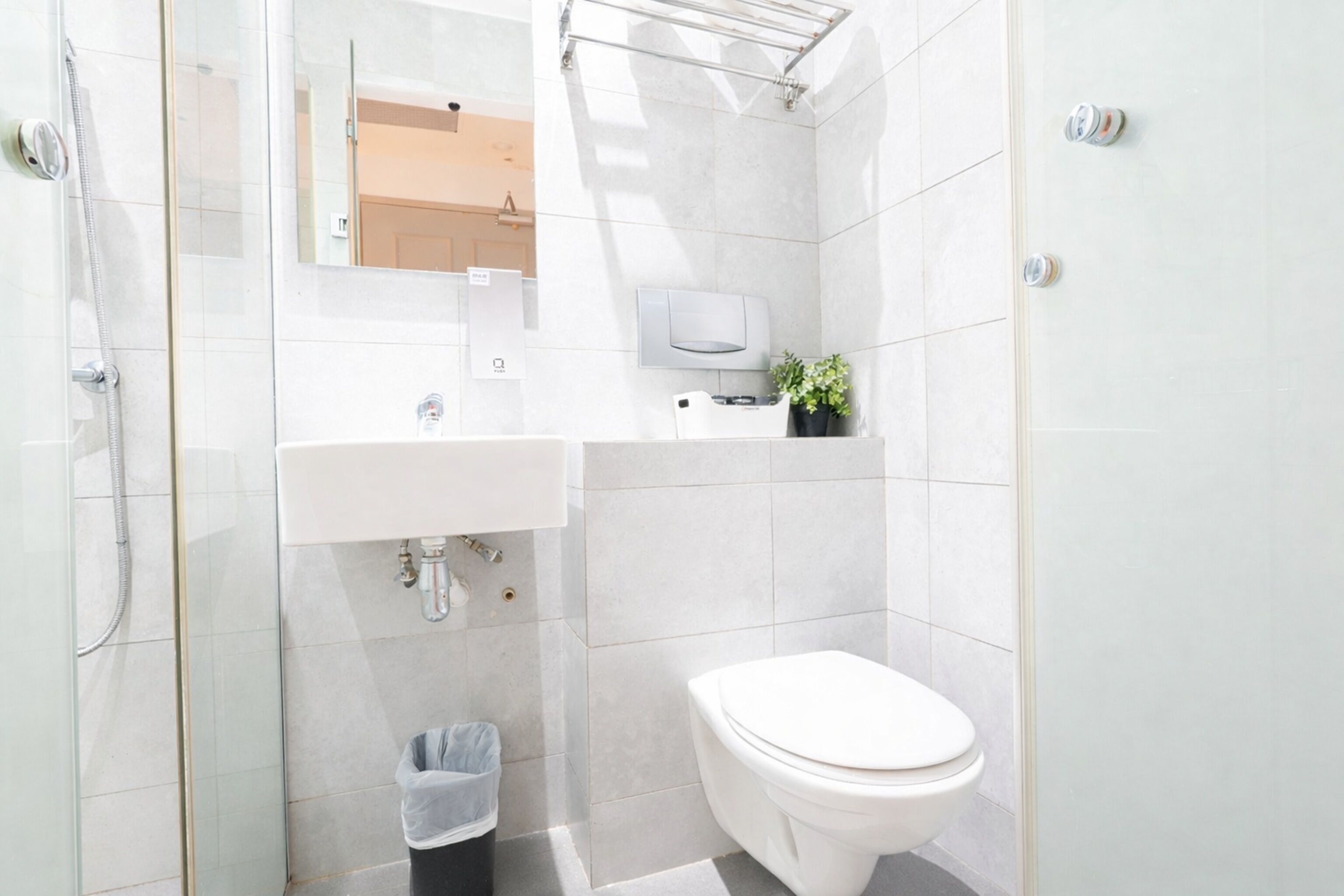 A modern bathroom with a glass-enclosed shower, a white sink, and a toilet.