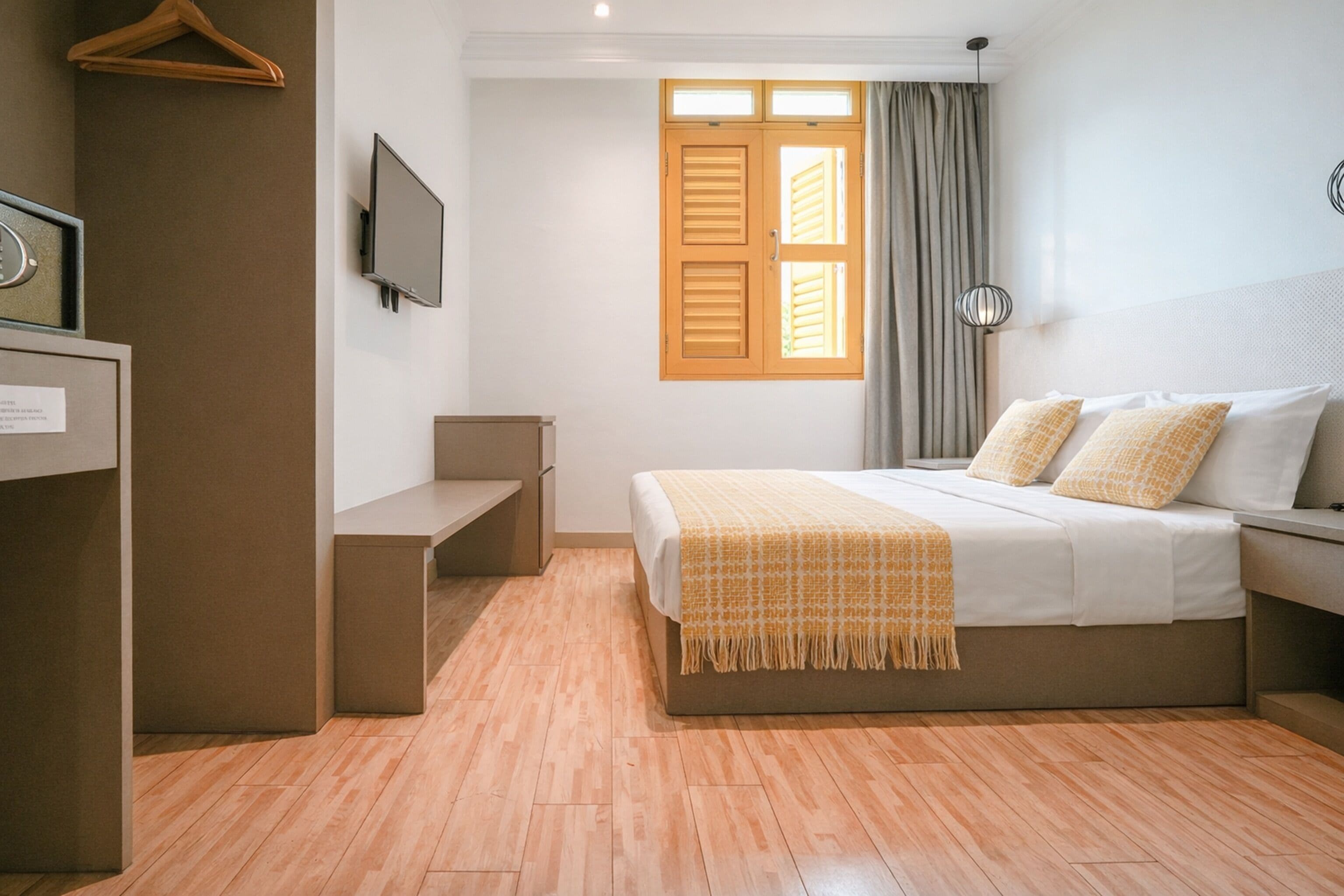 A neatly arranged hotel room with a bed, bedside table, and a television on the wall.