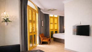 A hotel room with a bed, a TV, a chair, a sofa, and a potted plant. - A Hotel Joo Chiat (Singapore)