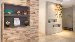 A reception area with a wooden reception desk, a welcome sign, and a colorful wall mural. - A Hotel Joo Chiat (Singapore)