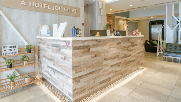 A hotel reception desk with a wooden design, a welcome sign, and a Wi-Fi symbol. - A Hotel Joo Chiat (Singapore)