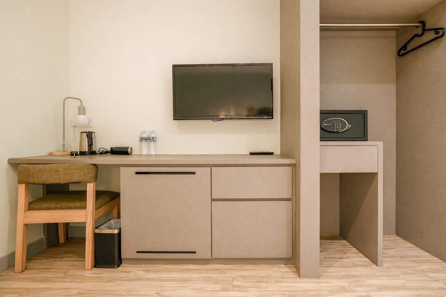 Una habitación compacta con escritorio, silla, televisión y caja fuerte.