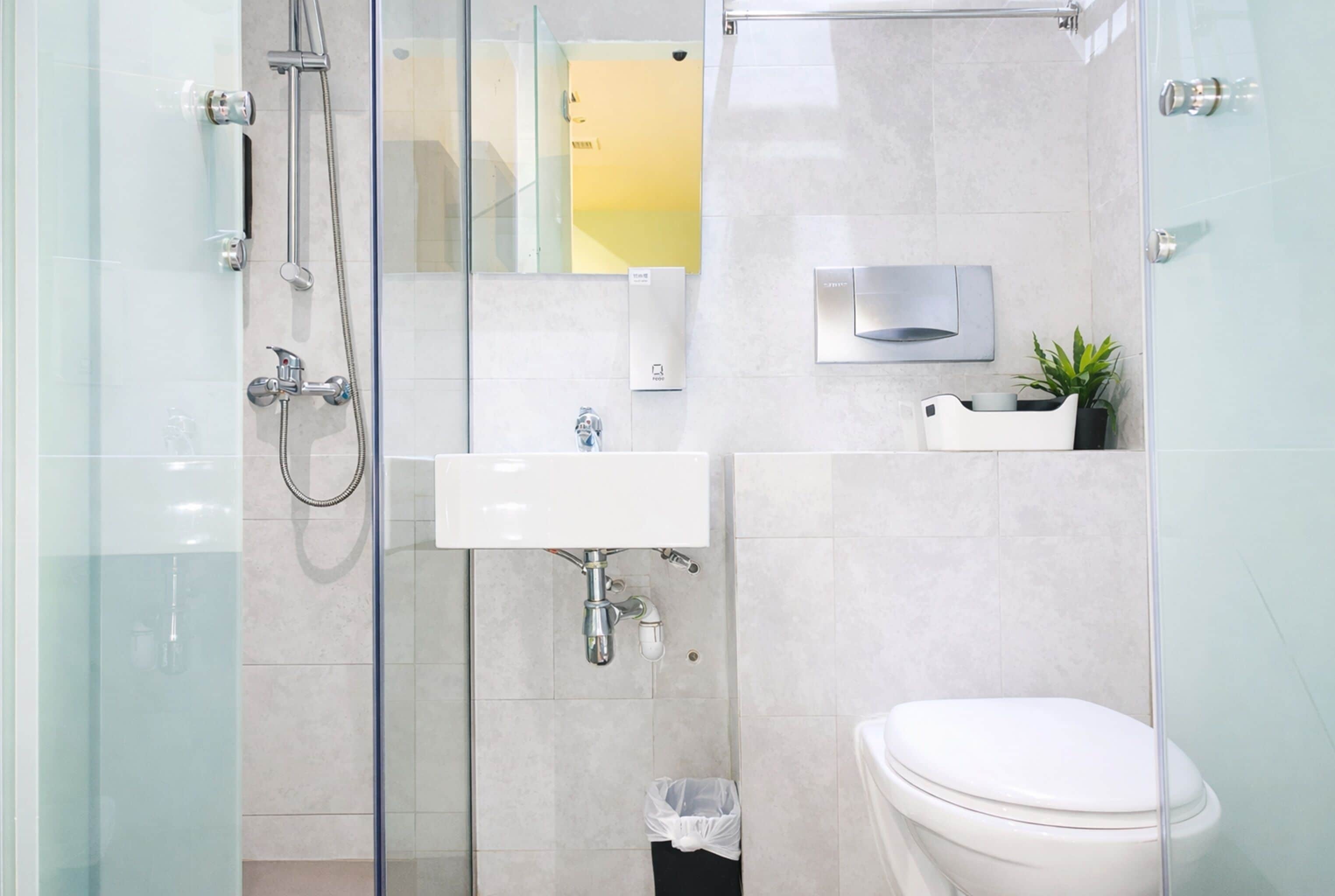A modern bathroom with a glass shower enclosure, a white sink, and a toilet.