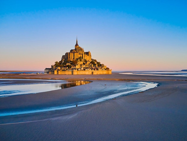 A cathedral-like structure on a coastal plain with a reflective water body in the foreground.