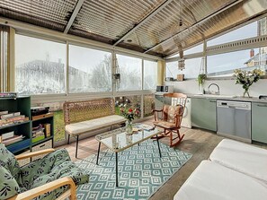 A modern kitchen with a built-in oven, a dining area with a bench, and a large window overlooking a snowy landscape.
