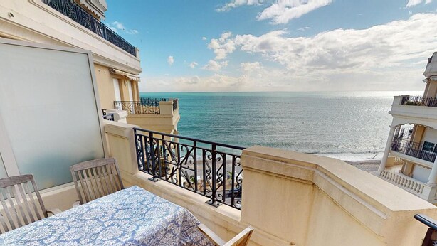 Un balcón con mesa y sillas, con vista al mar.