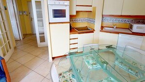 Una cocina funcional con mesa de vidrio, armarios blancos y microondas.