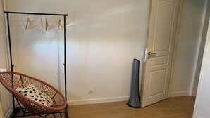 Huone, jossa on rottinkituoli, pyykiteline ja suljettu ovi.