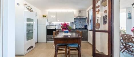 A modern kitchen with white cabinets, a wooden dining table, and a blue tiled backsplash.