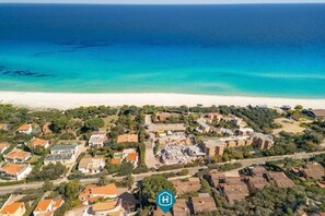 An aerial view of a coastal residential area with houses, a beach, and a clear view of the ocean. - Casa Ines Costa Rei, ocean view, 3 minutes from the beach. (Costa Rei)