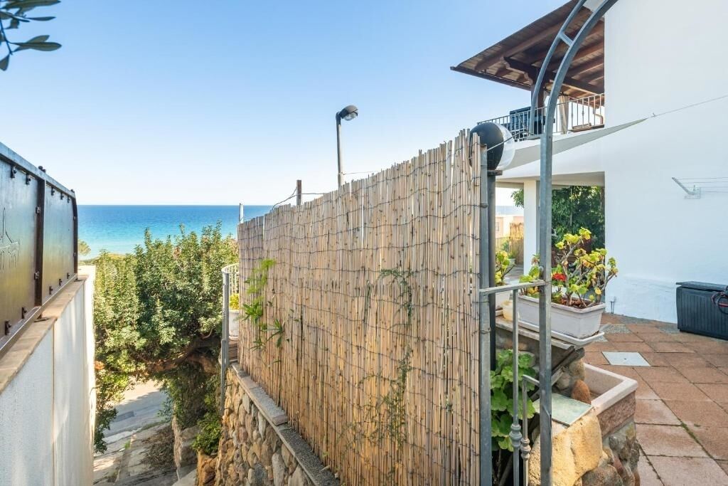 Ein Küsteneigentum mit Bambuszaun, einem Steinweg und einem Balkon mit Meerblick.