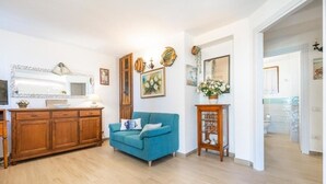 A living room with a wooden cabinet, a blue sofa, and a mirror on the wall. - Casa Ines Costa Rei, Sea View, 3 min from the Beach. (Costa Rei)