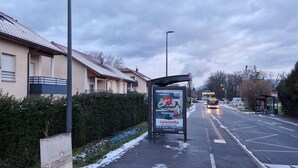A bus stop with a shelter, a sign for a restaurant, and a pedestrian and bicycle path sign.