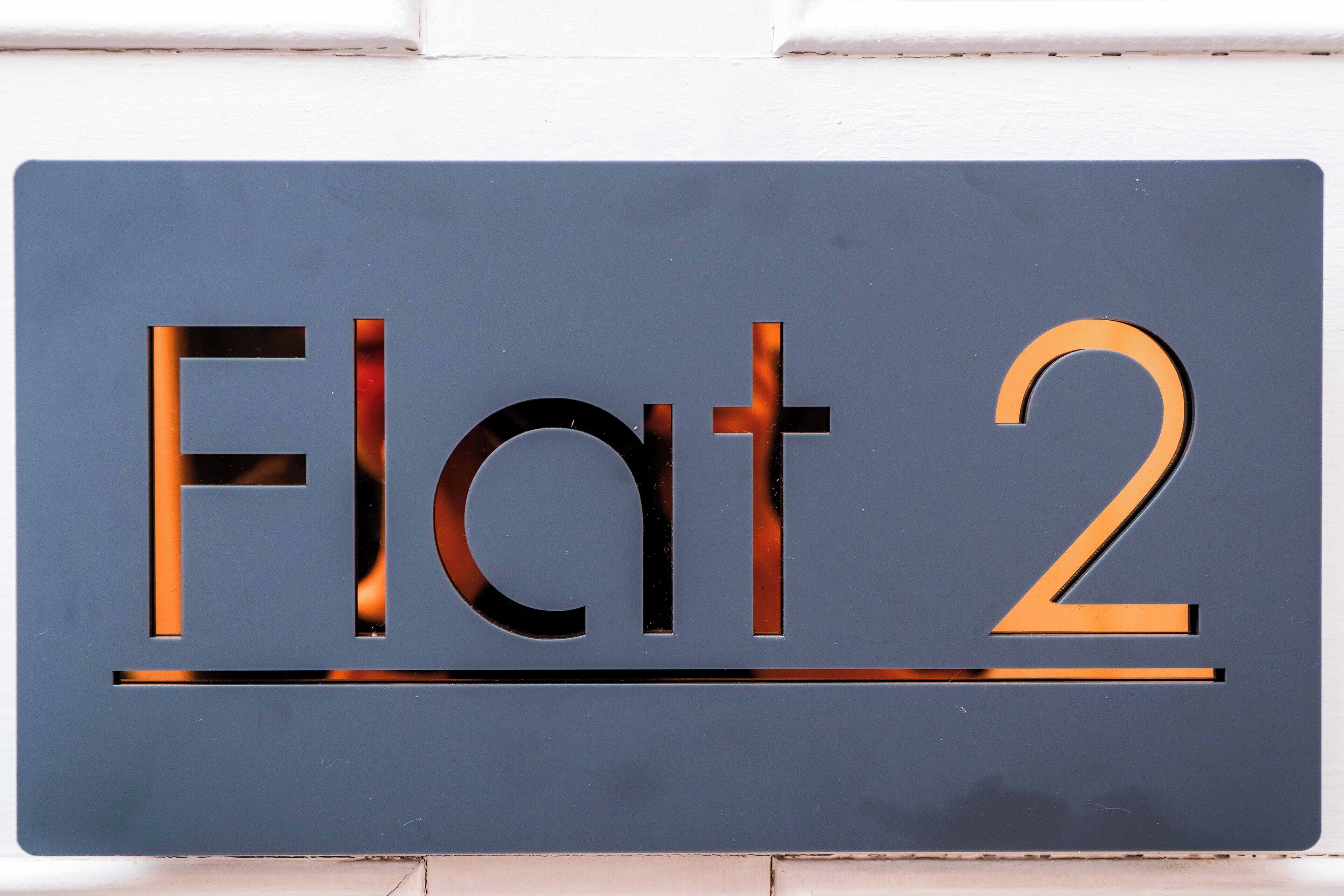 A sign with the text "Flat 2" in a modern font.