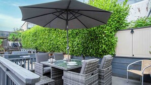 Eine Terrasse mit Korbmöbeln, einem Tisch und einem Sonnenschirm.