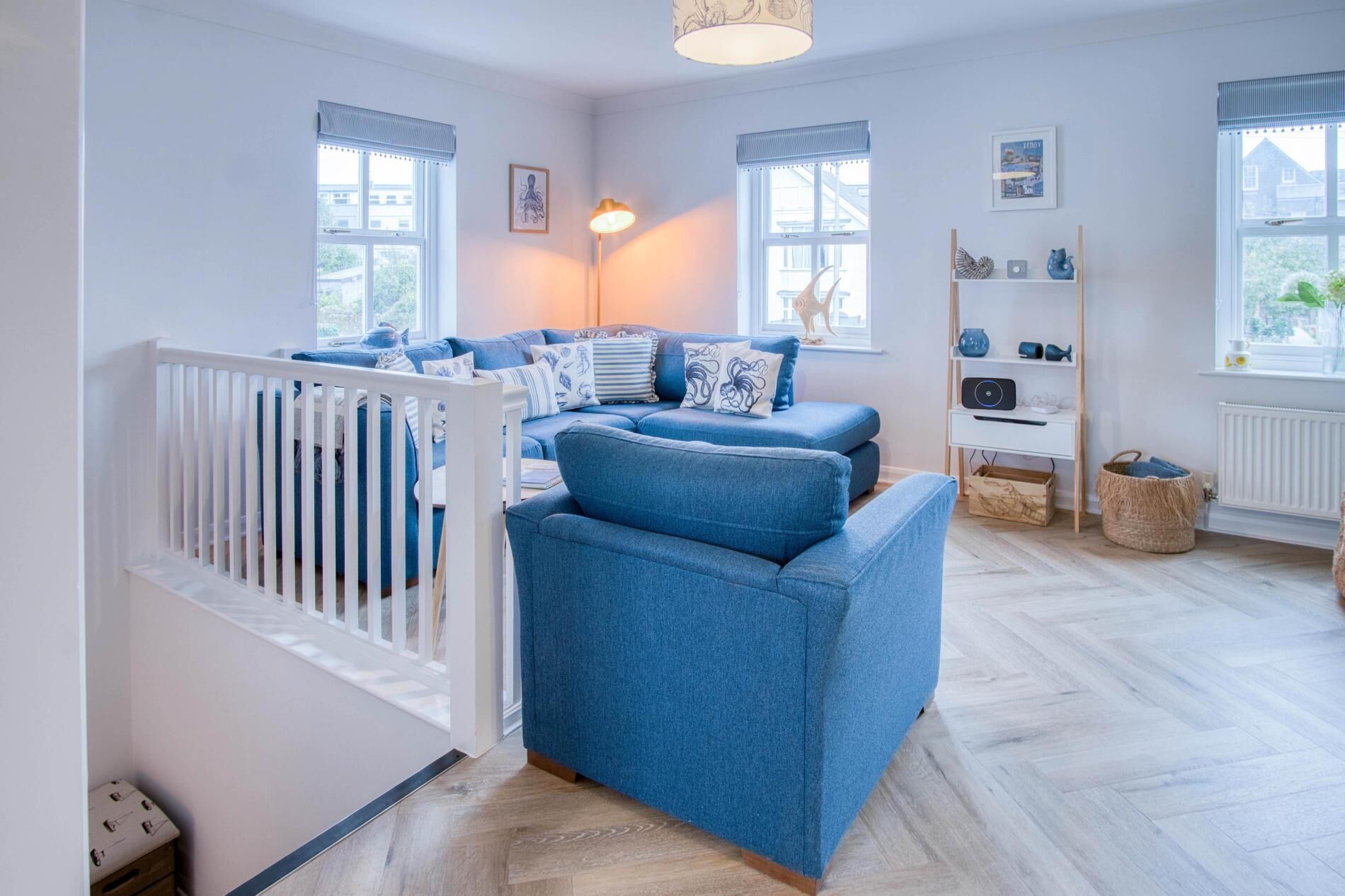 Een babykamer met een wit ledikant, een blauwe bank en een kleine witte tafel met een lamp.