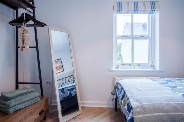 Une chambre à coucher avec un lit, un miroir, une commode en bois et une fenêtre donnant sur un beau paysage.