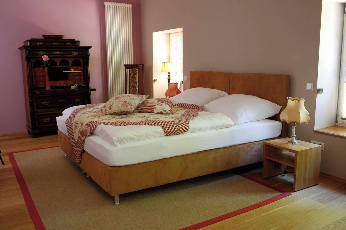 A neatly made bed with a wooden headboard and a bedside table with a lamp.