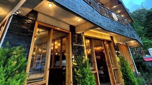 A two-story building with a balcony, large windows, and a wooden facade. - The Cozy Acorn Resort (Nainital)