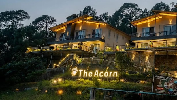 A two-story building with balconies, a sign reading "The Acorn," and a signboard for "Acorn Resort & Cafe." - The Cozy Acorn Resort (Nainital)