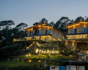 En toetages bygning med balkoner, et skilt der siger "The Acorn", og et skilt for "Acorn Resort & Cafe".