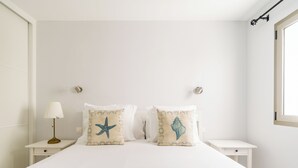 A neatly made bed with two decorative pillows, a bedside lamp, and a window with a view. - CITY FAMILY AUDITORIUM (Las Palmas de Gran Canaria)