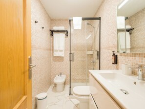 A modern bathroom with a glass shower enclosure, a white sink, and a toilet. - CITY FAMILY AUDITORIUM (Las Palmas de Gran Canaria)