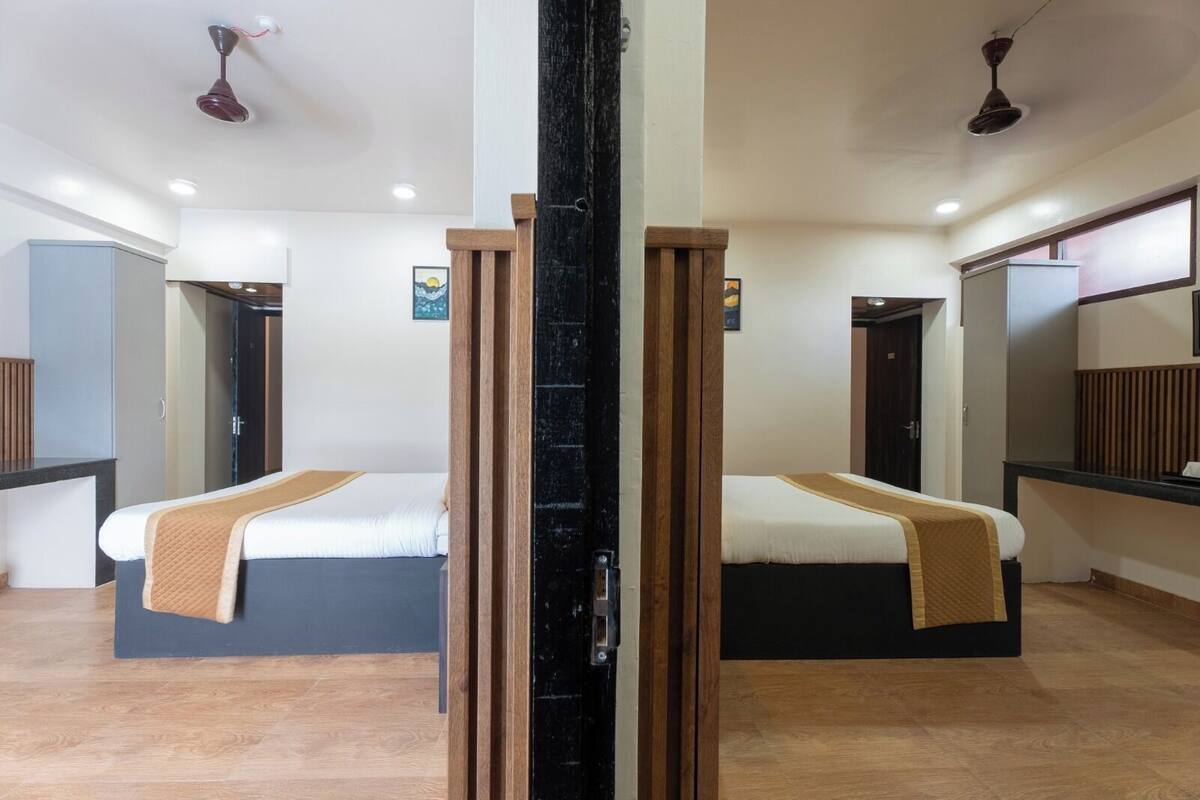 Quarto de hotel com duas camas, um painel de madeira e um espelho grande.