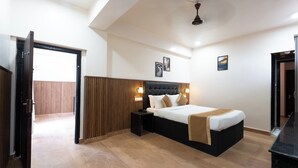A bedroom with a bed, bedside tables, a wooden panel wall, and a ceiling fan. - Hotel Mainak & Health Club (Port Blair)